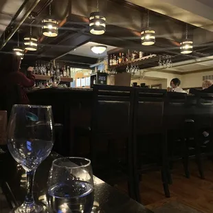 a restaurant with a bar and several empty wine glasses