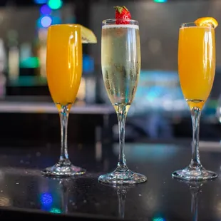 three glasses of champagne on a bar