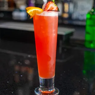 a cocktail with strawberries and orange garnish