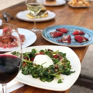a table with plates of food and a glass of wine