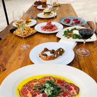 a wooden table with plates of food and glasses of wine