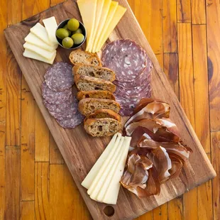 a cutting board with meat, cheese and olives