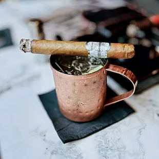 a copper mug with a cigar sticking out of it