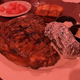 My finished t-bone with a baked potato, Texas toast, and a side of tomatoes from the salad bar.