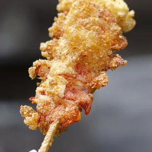 a hand holding a piece of deep fried fish