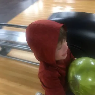 a young boy holding a green ball