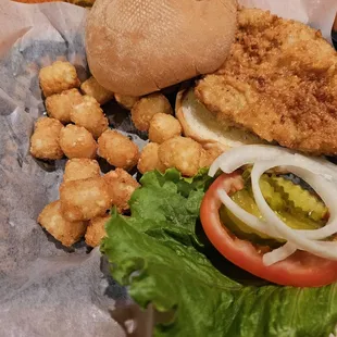 a chicken sandwich with lettuce, tomato, onion, and pickles