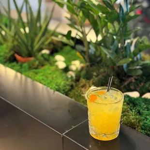 a glass of orange juice sitting on a ledge