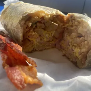 Ham/egg breakfast burrito with fries/rice/beans crispy bacon and salsa and jelly inside