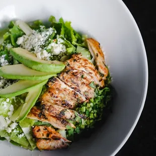 a bowl of salad with chicken, avocado, and feta cheese