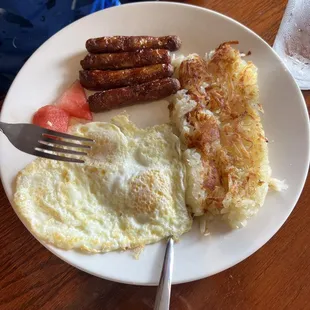 Eggs, hash browns and sausage. With two tiny cubes of watermelon.