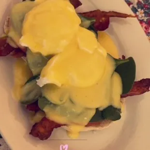 a plate of eggs benedict with bacon