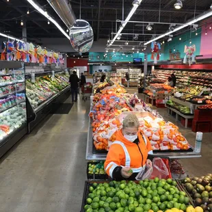 a man in an orange vest standing in front of a produce section