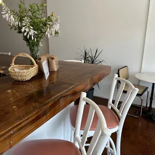 a wooden table with chairs and a basket of flowers