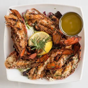a plate of grilled shrimp with a lemon wedge