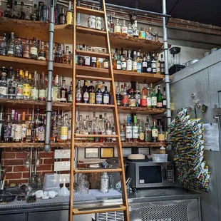 a ladder leaning against a wall of liquor bottles