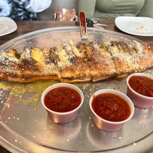 a pan of pizza with three dipping sauces