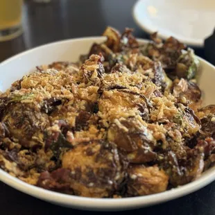 a bowl of food with a glass of beer in the background