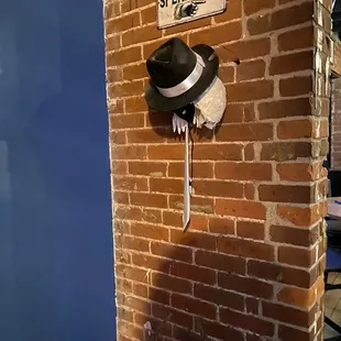 a hat hanging on a brick wall