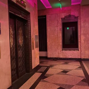 an empty hotel lobby with pink lighting