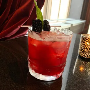 a close up of a drink with a blackberry garnish