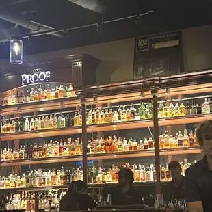 people sitting at a bar in front of a wall of liquor bottles