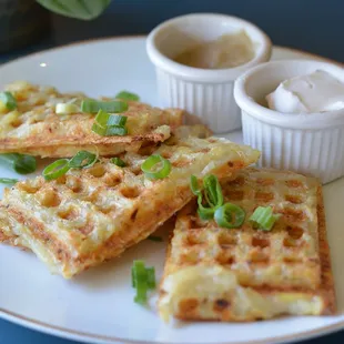a plate of waffles with sour cream and green onions