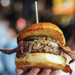 a hand holding a bacon burger