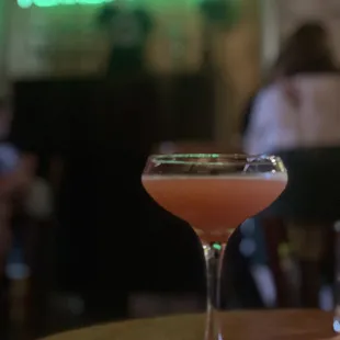 a pink cocktail in a glass on a table