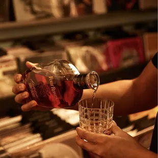 a person pouring a drink into a glass