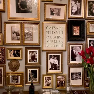 a table with a vase of flowers and pictures on the wall