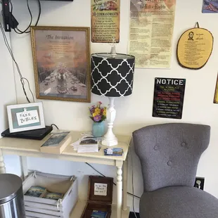a chair and a table with books and a lamp