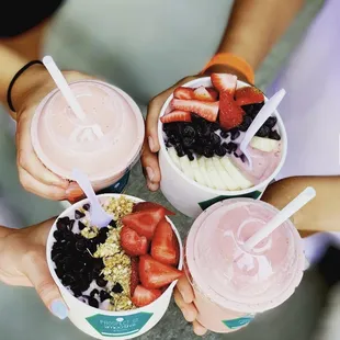 a group of people holding cups of smoothie