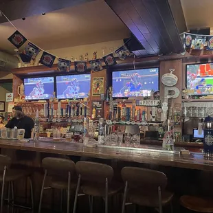 a man sitting at a bar with several televisions in the background