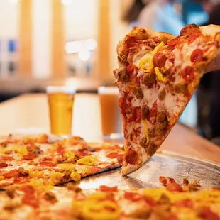 a person taking a slice of pizza