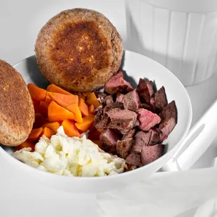 a bowl of meat, potatoes, carrots, and bread