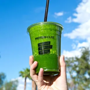 a hand holding a green smoothie