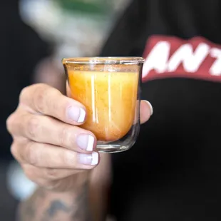 a person holding a glass of orange juice