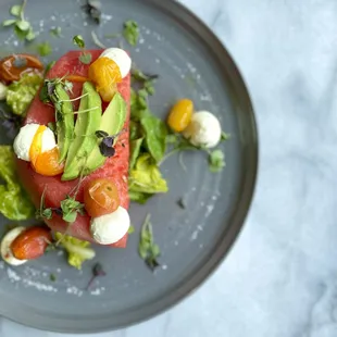 a plate of food with avocado, tomato, mozzarella, and mozzarella