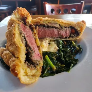 Beef fillet with mushroom duxelles, and prosciutto wrapped in puff pastry. Served with a side of garlic mashed potatoes and collard greens.