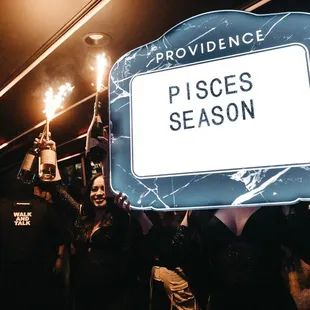 a crowd of people holding a sign that says pisces season