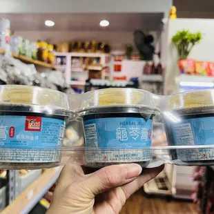 a hand holding three containers of food