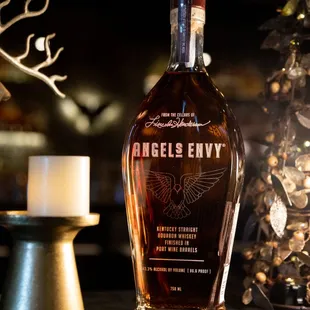 a bottle of angel&apos;s envy bourbon next to a candle