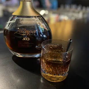 a glass of whiskey and a decanter on a table