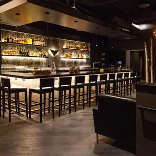 a dimly lit bar with black chairs
