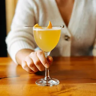 a woman sitting at a table with a cocktail in her hand