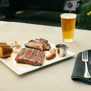 a plate of meat, bread, and beer