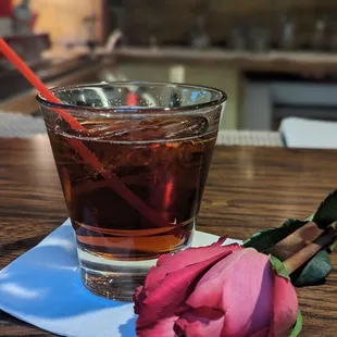 a rose and a drink on a napkin