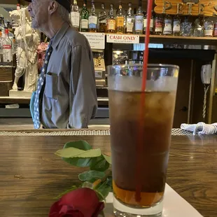 a man sitting at a bar with a rose in front of him