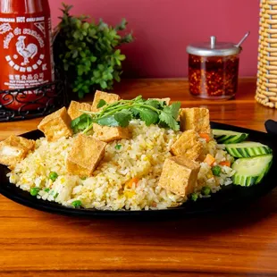 a plate of fried rice with tofu and cucumbers